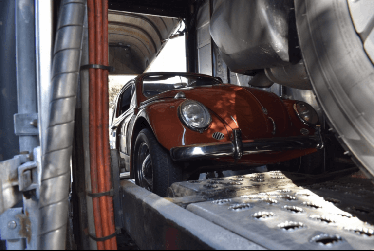 A brown 1960 Volkswagen Beetle that is inside a soft-side enclosed transport trailer. Whether you need to transport a classic car, an exotic car, or your daily driver, enclosed car shipping is for everyone.